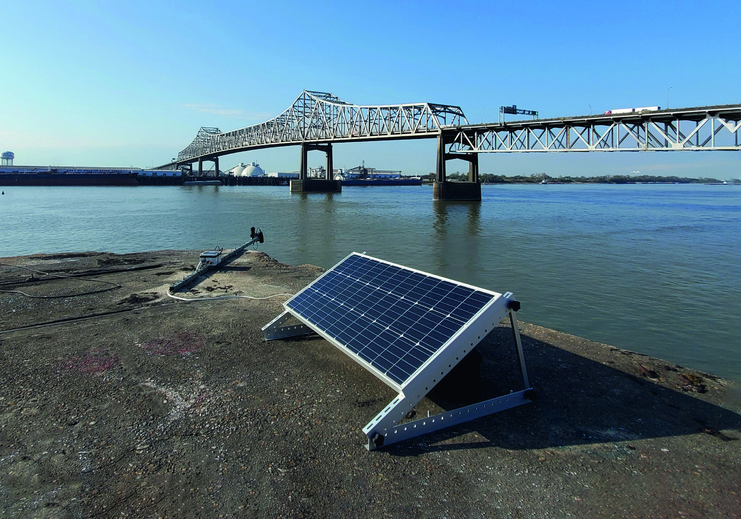 Aqualytics sensor with solar panel installed on the Mississippi riverbank in Baton Rouge, with the Horace Wilkinson Bridge in the background